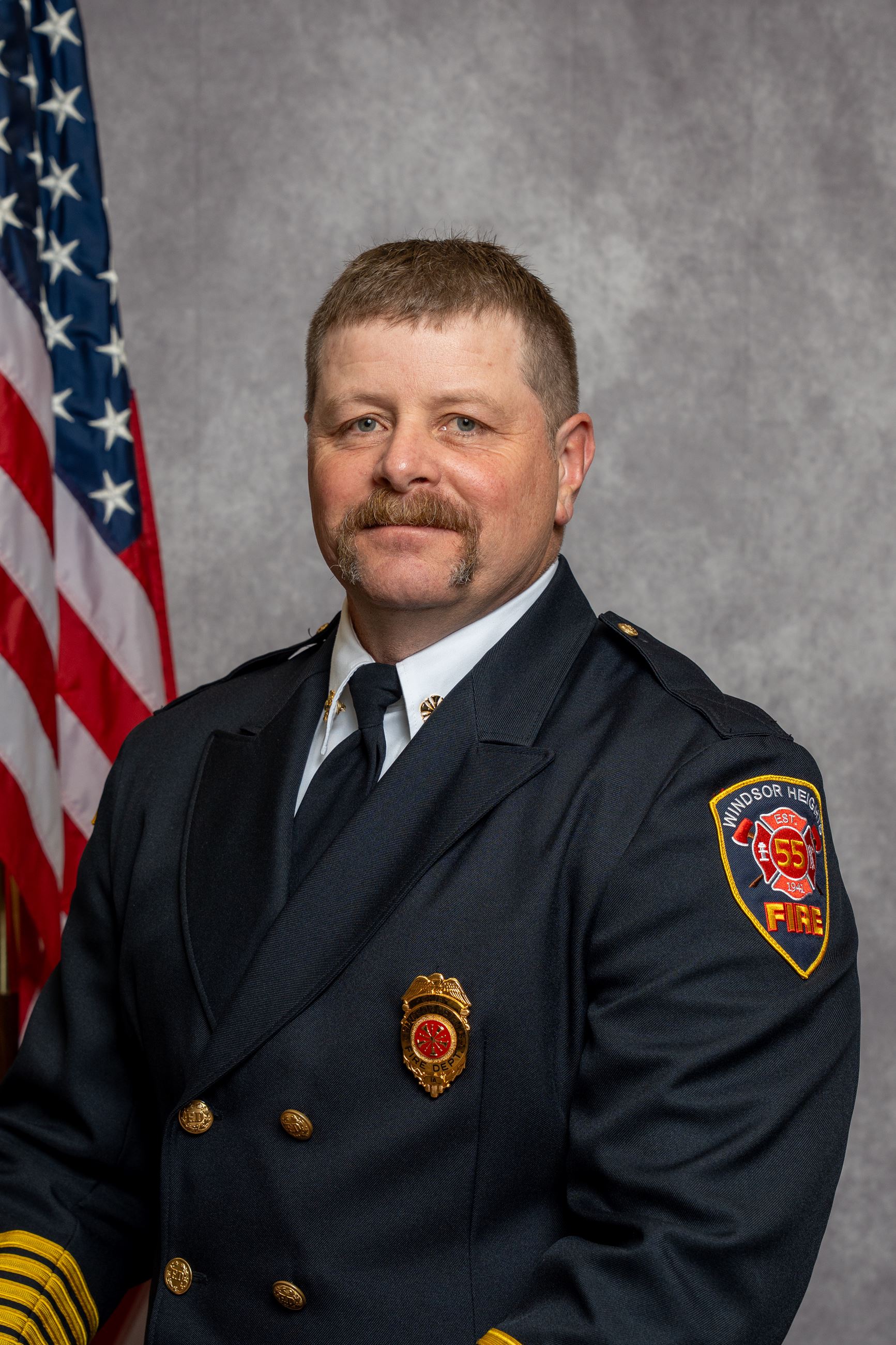 Windsor Heights Fire Department officer in dress uniform with American flag backdrop