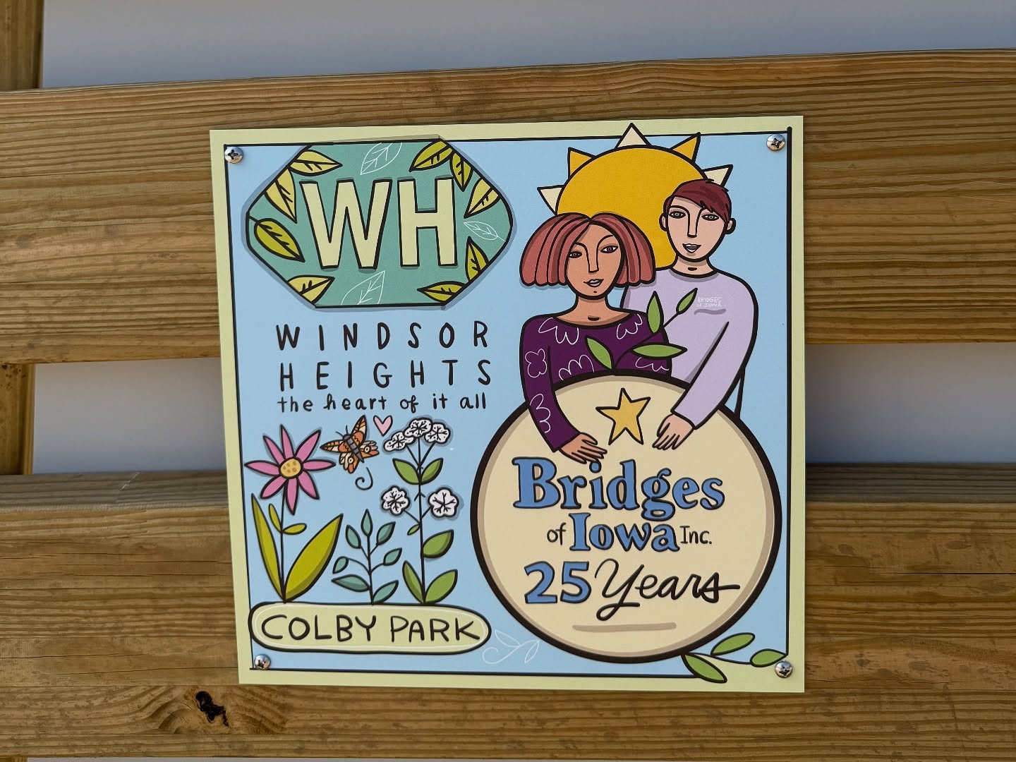 Decorative sign reading Windsor Heights, the heart of it all, honoring Bridges of Iowa 25 years